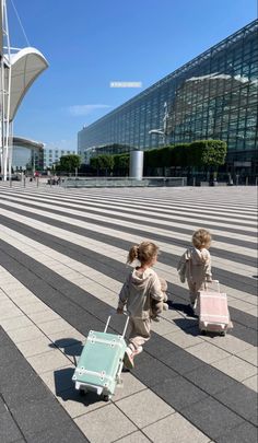 two small children pulling suitcases on the ground