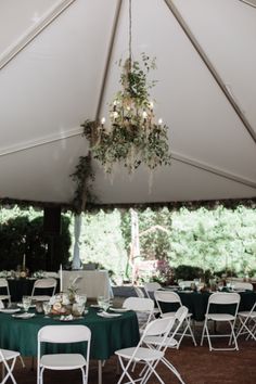 a large tent with tables and chairs set up for an outdoor wedding reception under a chandelier