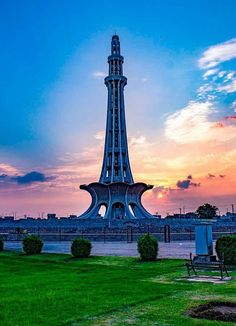 a tall tower sitting in the middle of a lush green grass covered field at sunset