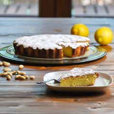 a piece of cake sitting on top of a plate next to lemons and pistachio