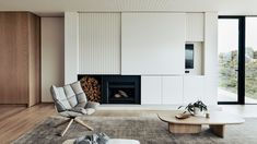 a modern living room with white walls and wood flooring on the side, along with a fireplace