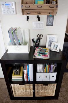 a book shelf with some books and other items on it next to a wall mounted phone