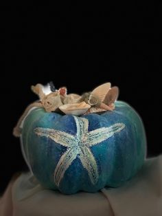 a blue pumpkin decorated with shells and starfish