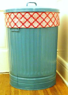 a blue trash can sitting on top of a hard wood floor