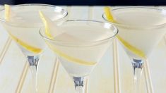 three martini glasses with lemon wedges in them