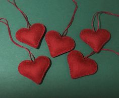 three red hearts hanging from strings on a green surface