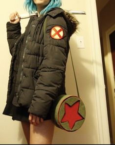 a woman with blue hair is holding a baseball bat and wearing a jacket that has an x on it