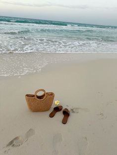 a pair of flip flops sitting on top of a beach next to a basket