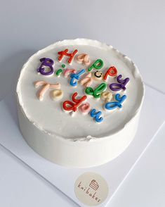 a birthday cake with white frosting and colorful letters