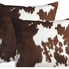 two brown and white cowhide pillows sitting next to each other