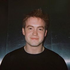 a man in black shirt smiling at the camera