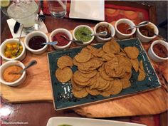 a wooden table topped with plates and bowls filled with different types of food next to dipping sauces