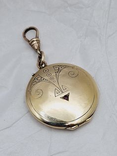 This is a fabulous antique locket that is perfect for your modern wardrobe! This large round gold-filled locket pendant features an extra special Art Deco inspired design on the front with a genuine garnet accent stone.  The reverse side has the original owner's monogram.  Inside is a portrait of a lovely young woman along with a hand sketched drawing of a cherub.  I do not know if anything is written on the reverse, as I did not want to disturb the tiny drawing.  Both gold filled frames and pic Luxury Antique Locket Jewelry, Antique Coin Pendant Jewelry, Ornate Yellow Gold Medallion Locket Necklace, Elegant Bronze Round Locket Necklace, Antique Engraved Round Locket Necklace, Antique Yellow Gold Locket Necklace, Antique Round Engraved Locket Necklace, Yellow Gold Medallion Locket Amulet Necklace, Yellow Gold Medallion Locket Necklace Amulet