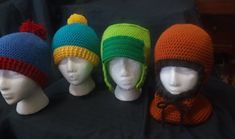 four knitted hats are lined up on mannequin heads