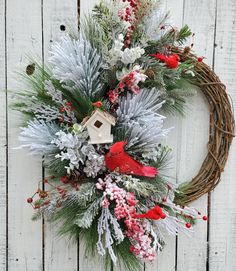 a christmas wreath hanging on the side of a white wooden wall with red and green decorations