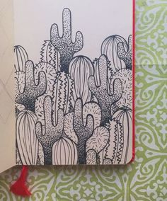 an open notebook with a drawing of cactuses on the cover and red string attached to it