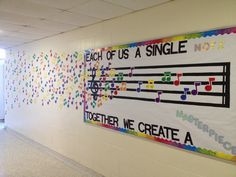 a bulletin board with music notes on it in a hallway next to a door that says each of us a single note together we create a story