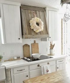 a kitchen with white cabinets and wooden counter tops in the center, surrounded by wreaths