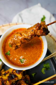 the skewer is being used to eat some food on the plate with chopsticks