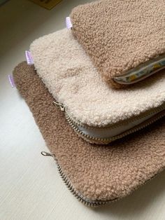 three zippered purses are stacked on top of each other, one has a cell phone in it