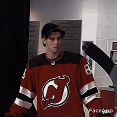 a young man in an orange jersey is holding a hockey stick and looking at the camera