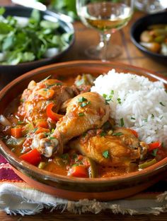 a bowl filled with rice and chicken next to other food on a tablecloth covered place mat