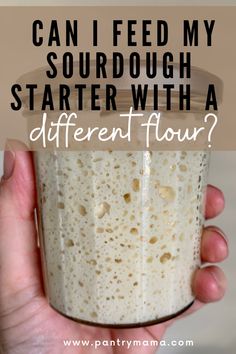 a person holding up a glass with milk in it and the words can i feed my sourdough starter with a different flour?