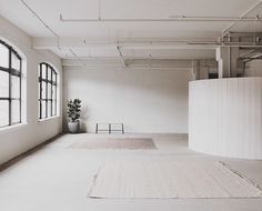 an empty room with large windows and rugs on the floor