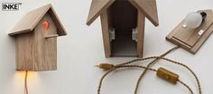 two wooden birdhouses with lights attached to them on a white wall next to a cord