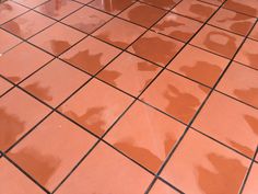 an orange tiled floor with black grouting on the top and bottom tiles in different colors