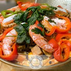 a plate full of shrimp and vegetables on a wooden table