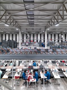 an assembly line in a factory with workers working on their laptops and desks