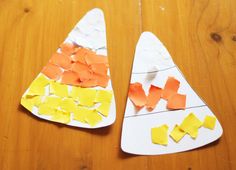 two paper plates with cut out pieces of orange and yellow paper on them sitting on a wooden table