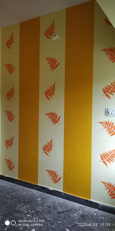 an orange and white striped wall with red leaves painted on the wall next to it