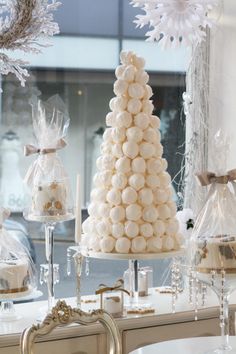 a table topped with lots of white candies next to a tall christmas tree covered in snowflakes