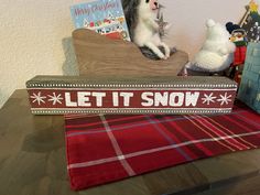 a wooden sign that says let it snow with two stuffed animals in front of it