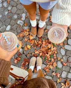 two people standing next to each other with their feet on the ground holding water cups