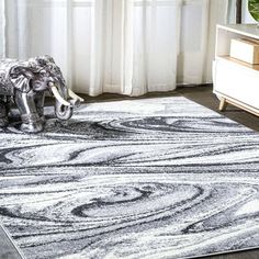 an elephant statue on top of a rug in front of a window with white curtains