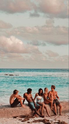 four people sitting on the beach talking to each other