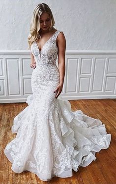 a woman in a white wedding dress standing on a wooden floor with her hand on her hip