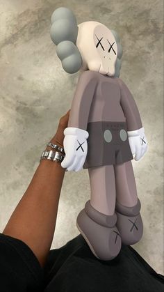 a person holding a toy in the shape of a human being held up by someone's hand