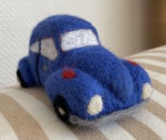 a small blue toy car sitting on top of a couch cushion with white and brown stripes