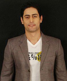 a man standing in front of a black background wearing a white t - shirt and jacket