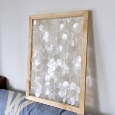 a wooden frame with buttons in it on top of a blue couch next to a white wall