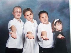 three children are posing for a photo with their hands in the air and one child is pointing