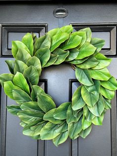 a close up of a wreath on a door with green leaves in the shape of a cross