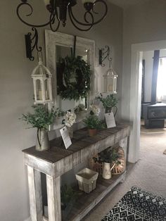 a table with some potted plants on top of it next to a mirror and chandelier