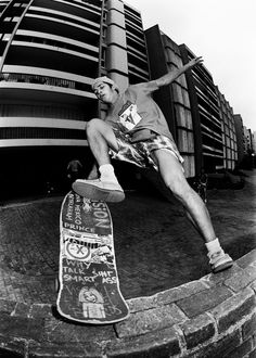 a man riding a skateboard up the side of a brick wall next to a tall building