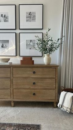 a dresser with pictures on the wall above it and a plant in a vase sitting on top