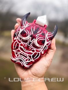 a hand holding a red and white object with horns on it